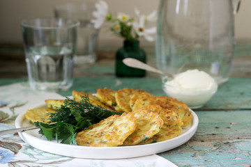 Pancakes with zucchini and sweet corn, served with sour cream, parsley and dill. Vegetarian food.