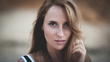 closeup dramatic portrait of young beautiful american woman face with freckles