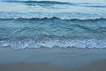 sea waves with white foam and part of the shore with gray sand