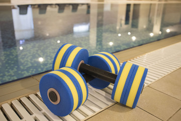 foam dumbbells for sports lie in the pool, the concept of a healthy lifestyle
