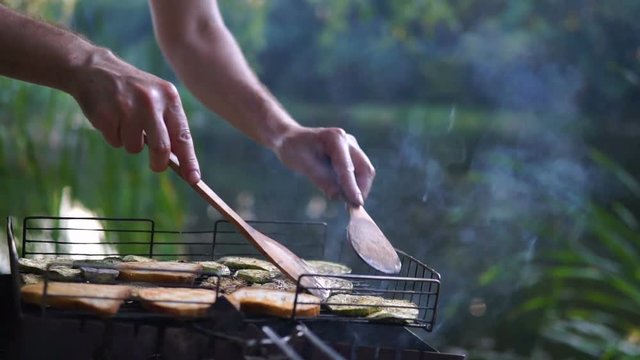 man bakes bread and vegetables on barbecue outdoor