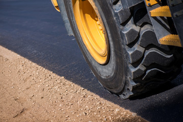 Macro shot of a wheel of loader truck during road construction works on side of highway. Freshly...