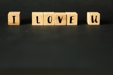 Obraz premium Word concept - I LOVE U build from wooden cubes with letters, selective focus, black background, free copy space