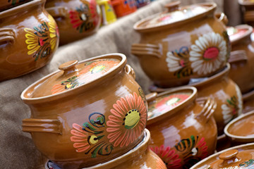 Traditional Romanian painted clay pots used for Easter meals. Decorations and ornaments on bowl. Beautiful kitchen decor. People buying kitchen supplies in local market