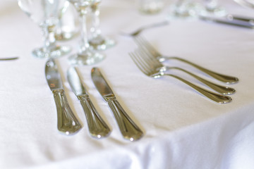 Forks and knifes on a wedding table with plate and glasses.