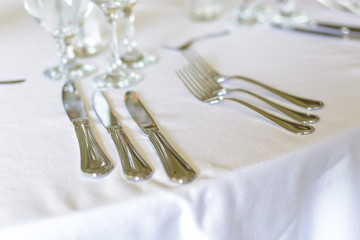 Forks and knifes on a wedding table with plate and glasses.