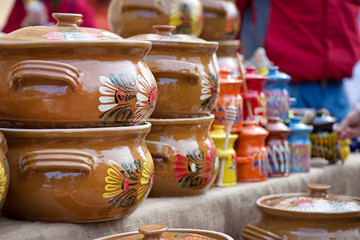 Traditional Romanian painted clay pots used for Easter meals. Decorations and ornaments on bowl. Beautiful kitchen decor. People buying kitchen supplies in local market