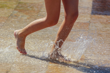The legs of a girl in the water in a fountain