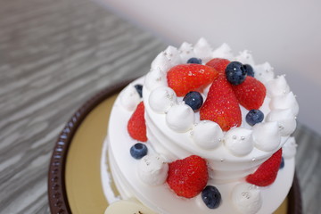 Birthday cake full of cream with strawberry and blue berry on top