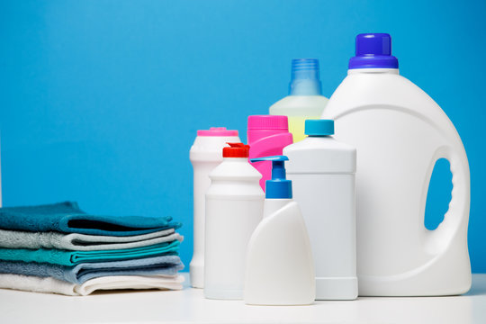 Photo of different bottles of cleaning products and colored towels isolated on blue background