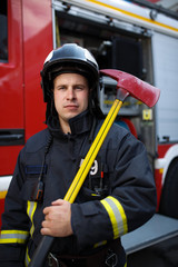 Photo of serious fireman with ax on background of fire engine