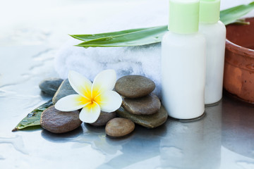 Obraz na płótnie Canvas Towel and two cream tubes with flower and stones. Body care and spa concept
