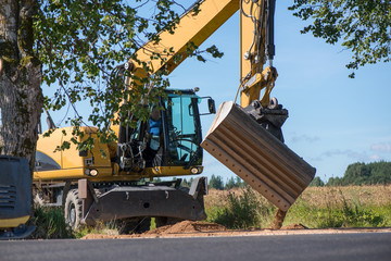 Frontal excavator pushing a gravel pile around at a quarry site, next to road construction site  
