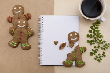 Ginger bread cookies on craft paper background . Blank notepad with leaf of fern. Coffee Christmas mockup. Top view.
