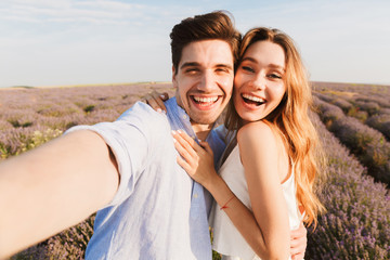 Cheery young couple taking a selfie while hugging