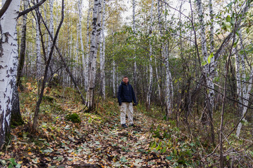 man in a jacket is in the Birch forest