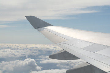 Fototapeta na wymiar Airplane wing fliying above the clouds in clear sky
