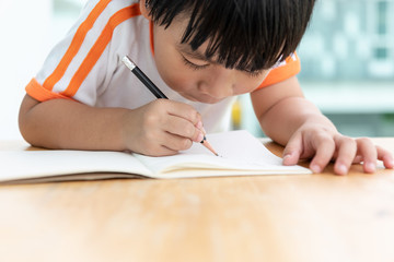 asian children boy writing paper .Happy kid drawing pencil on a book with copy space.