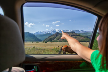 Naklejka premium Young tourist woman showing his finger the direction of traffic for a further adventure on top of a mountain in car covered with snow against a blue sky background.Travel Lifestyle and survival