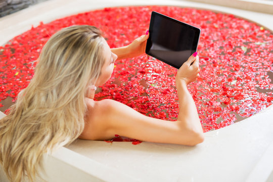 Woman Reading On Tablet While Relaxing In Bath