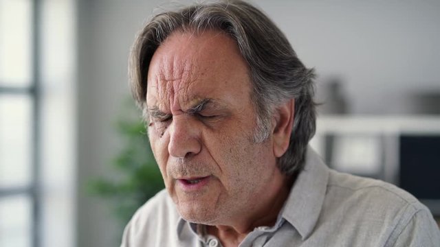 Old man with sensitive teeth holding a glass of cold water