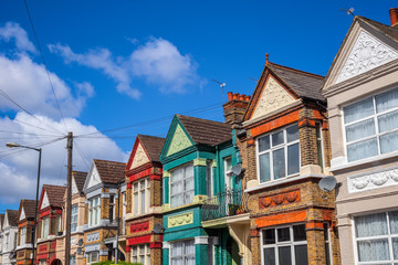 A row of colourful terraced houses in London with overhead cable lines