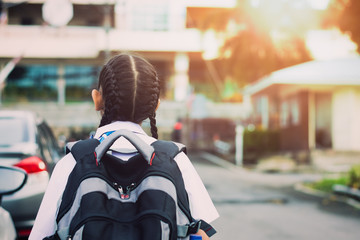 Little girl walking into school with backpack. Education concept.
