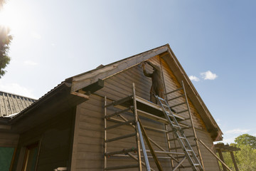 Senior man building a house by standing on scaffolding