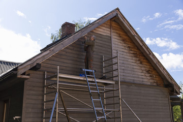 Senior man building a house by standing on scaffolding