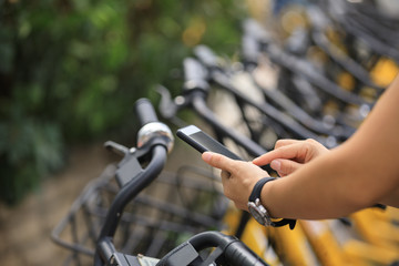 Fototapeta na wymiar People hands using smartphone scanning the QR code of shared bike in city