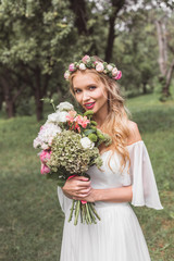 beautiful young blonde bride holding bouquet of flowers and smiling at camera