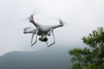 Naklejka na ściany i meble White drone with camera flying over forest