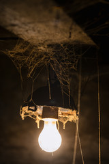 Light of old lamp in a creepy room with cobwebs