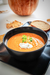 Pumpkin and carrot soup with cream and parsley