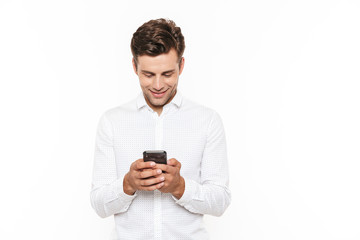 Young man with short dark hair chatting or typing text message with smartphone, isolated over white background