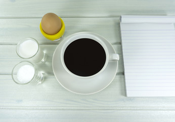 Fototapeta na wymiar Hot coffee in the morning with milk in glass and Soft-boiled egg in cup on a white wooden floor background,Top view Copy Space.