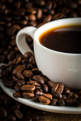 Coffee cup and beans on a rustic background. Coffee Espresso and a piece of cake with a curl. Cup of Coffee and coffee beans on table.