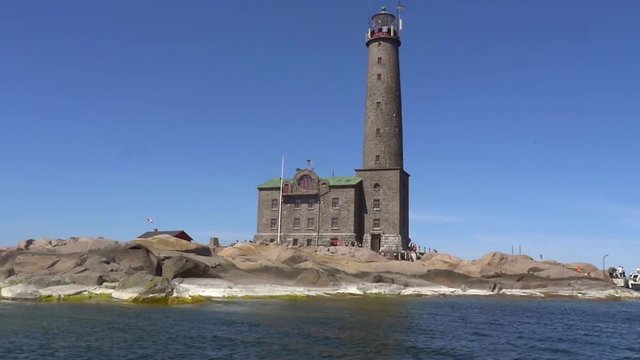 Pov view from a boat of a grand lighthouse, on a rocky island bengtskar, on a sunny summer day, in saaristomeri national park of the finnish archipelago, in Varsinais-suomi, Finland