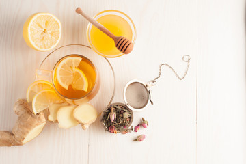 Closeup of cup of tea with tea leaves, mint on vintage wooden background. Black herbal tea with lemon, ginger and honey. hot winter drink