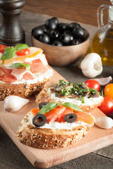 Italian tomato and cheese bruschetta. Tapas, antipasti with chopped vegetables, herbs and oil on grilled ciabatta and baguette bread.