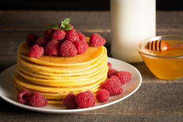 Tasty pancakes with blackberries, banana, raspberries, eggs, honey and maple syrup on wooden background. Morning breakfast concept.