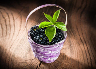 Blackberries in basket on vintage wooden background