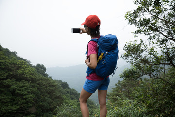 Woman Hiking In Forest Taking A Selfie With mobile phone