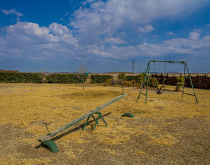 Fototapeta na wymiar Empty playground against a background of blue skies and white clouds image with copy space in landscape format