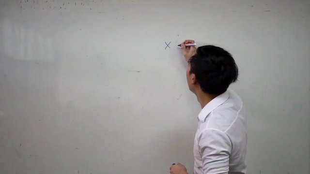 Young handsome Asian math teacher writing a math formula equation on white board during lesson. Education and school concept