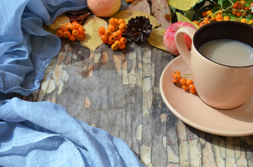 Flat lay of composed cup with black coffee on wood table with ripe berries of rowan and dark foliage. Cappuccino or latte or tea on a vintage table. fallen leaves, ripe apples, berries. Copy space