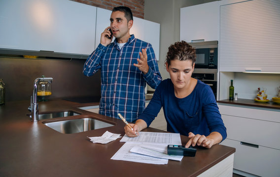 Angry young man arguing at phone while a woman calculating their bank credit lines. Financial family problems concept.