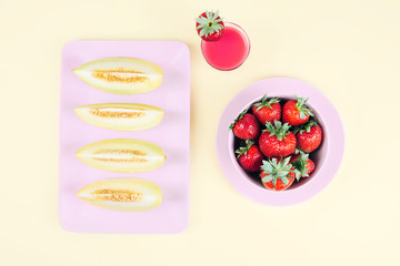 Fresh strawberries in bowl and melon on pastel yellow background.