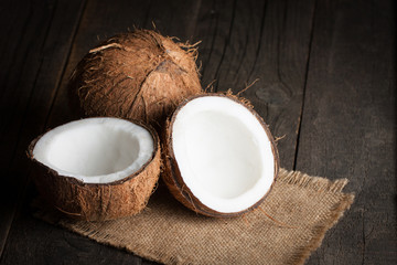 Ripe half cut coconut on a wooden background.  Coconut cream and oil.