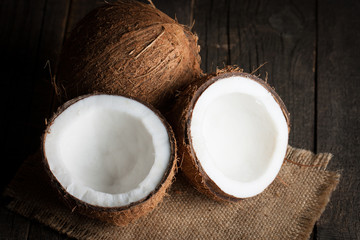 Ripe half cut coconut on a wooden background.  Coconut cream and oil.